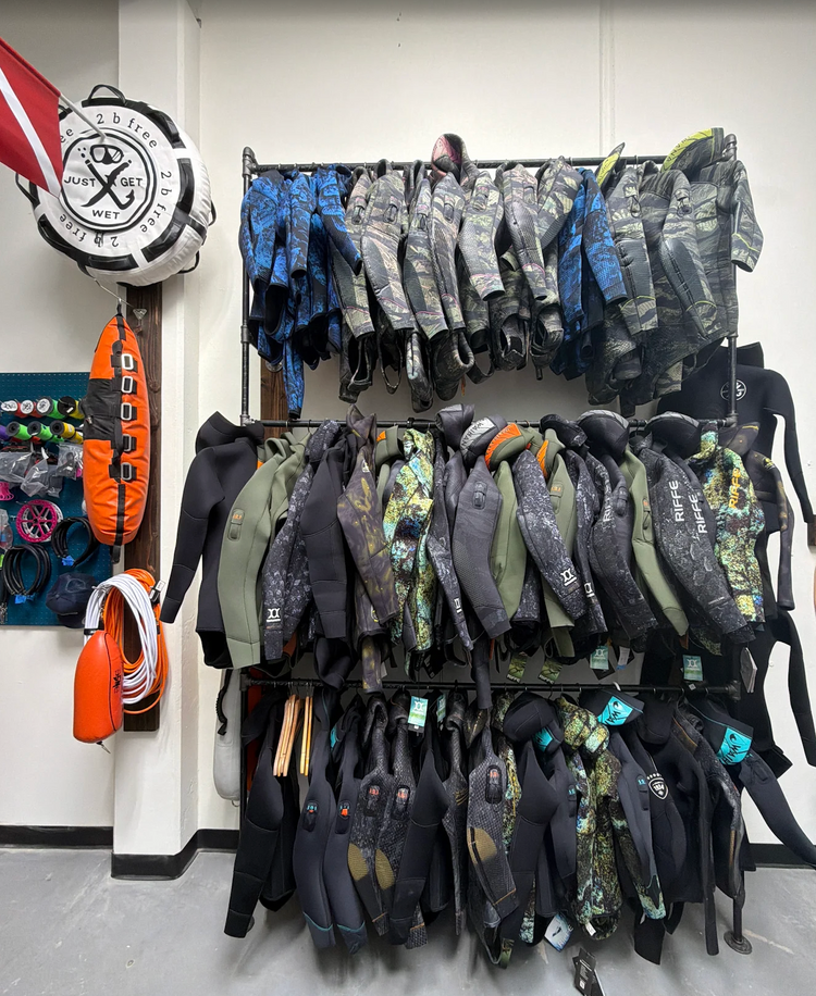Racks of freediving and spearfishing wetsuits on the wall of the Just Get Wet shop